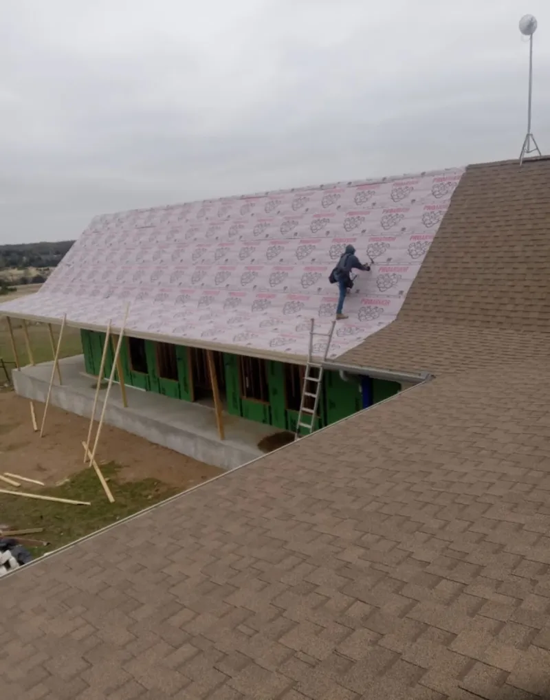 Worker preparing underlayment for a metal roof installation in Edinboro